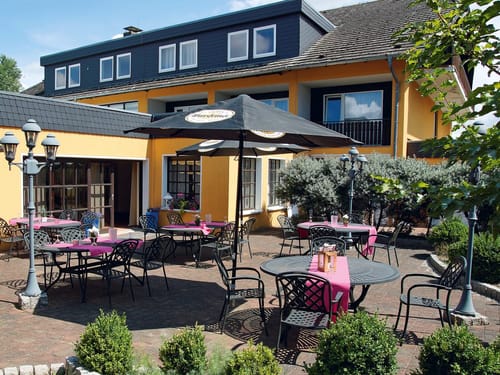 gemütliche Hotelterrasse mit verschiedenen Tischgruppen und Sonnenschirmen