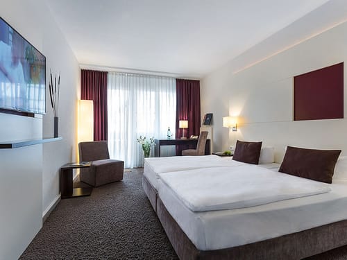 Doppelzimmer mit Boxspinhgbett, Sessel und Tisch