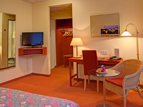 Wohnbereich im Doppelzimmer mit Sessel, Stuhl, Schreibtisch, Fernseher und Spiegel