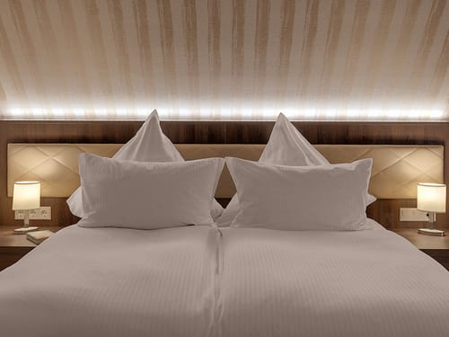 Doppelbett mit weißer Bettwäsche und Nachttischlampen