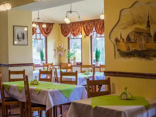 Hotelrestaurant mit verschiedenen Tischgruppen und grünen Mitteldecken