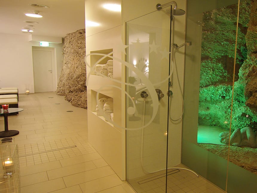 Wellnesslandschaft mit Dusche, Ablage für Handtücher und Relaxliegen