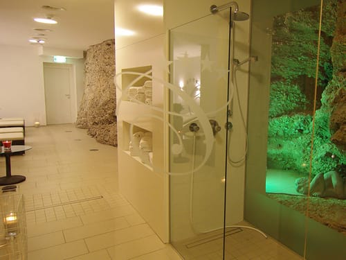 Wellnesslandschaft mit Dusche, Ablage für Handtücher und Relaxliegen