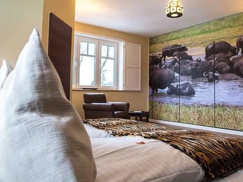 Zimmer mit afrikanischem Safari-Dekor und großem Fotowandbild mit Wasserbüffeln.