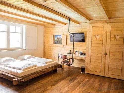 Gemütliches Schlafzimmer im Chalet-Stil mit Holzmöbeln und Ski-Lift-Stuhl