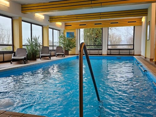 Innenpool mit Liegestühlen und großen Fenstern