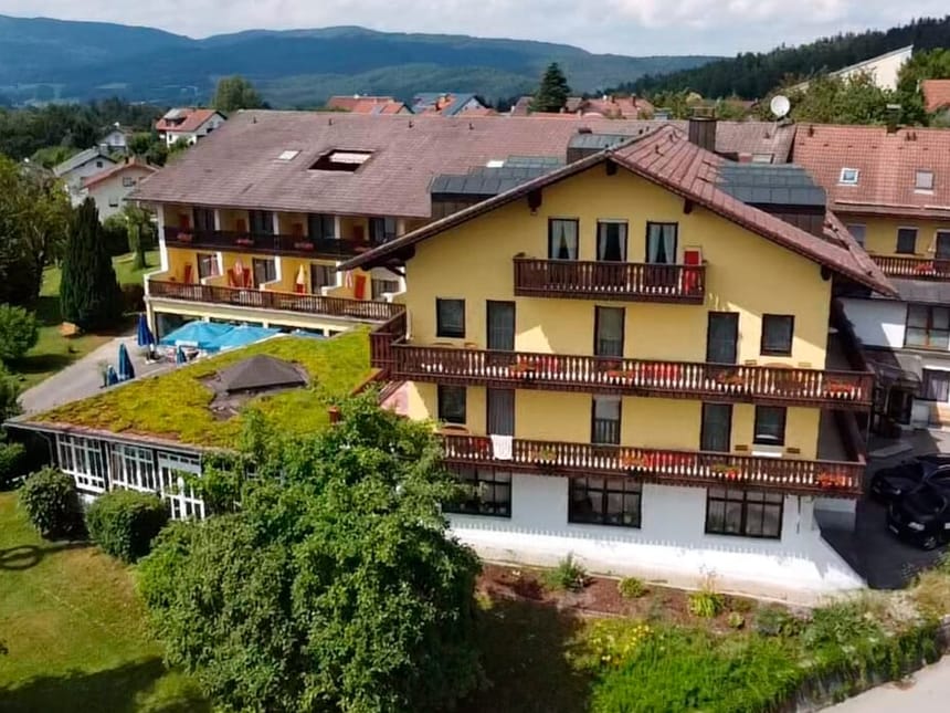Panoramaaufnahme eines gelben Hotelgebäudes mit grüner Dachbegrünung und umliegender Landschaft.