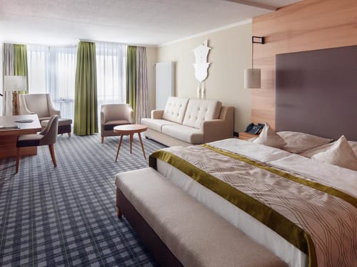 Modernes Hotelzimmer mit Doppelbett, Schreibtisch und Sitzecke