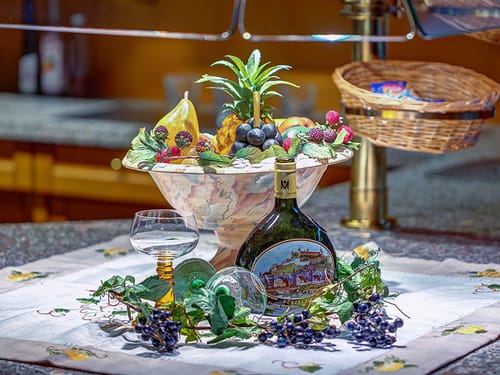 Boxbeutel Wein mit Weinglas und Schale Obst auf dem Buffet