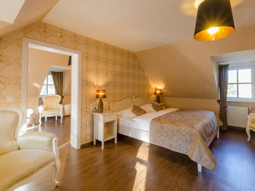 Doppelzimmer mit Doppelbett, Sessel, Nachttisch und extra Wohnbereich
