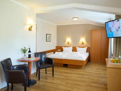 Entdecken Sie ein stilvolles Hotelzimmer mit gemütlichem Doppelbett, einer einladenden Sitzecke und moderner Ausstattung. Perfekt für Ihren erholsamen Aufenthalt.