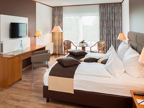 Modernes Doppelzimmer mit TV, Tisch und Sitzmöglichkeiten