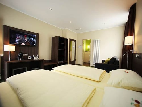 Wohn und Schlafbereich im Doppelzimmer mit Doppelbett, TV, Sessel und Schreibtisch