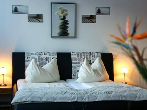 Entdecken Sie ein stilvoll eingerichtetes Schlafzimmer mit einem komfortablen Doppelbett, Zen-inspirierter Wanddekoration und stimmungsvoller Beleuchtung für eine erholsame Atmosphäre.