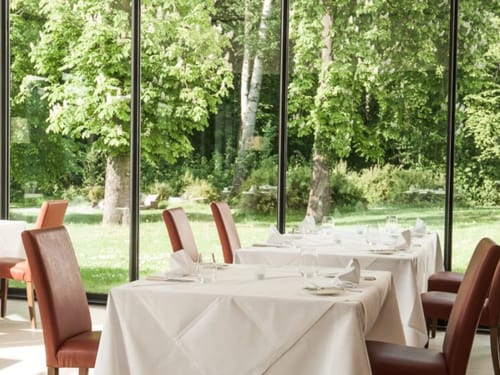 Elegantes Restaurant mit Panoramafenstern und Blick auf einen grünen Garten.
