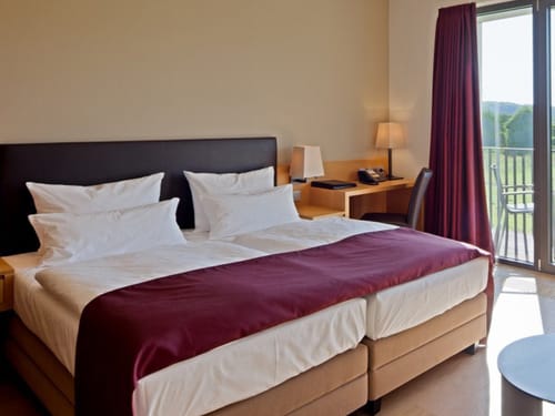 Elegantes Hotelzimmer mit Doppelbett, Schreibtisch und Balkon