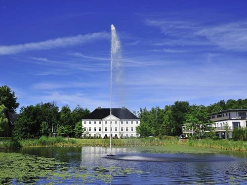 Historisches Schloss mit Teich und Springbrunnen an einem sonnigen Tag