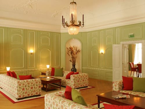Elegantes Wohnzimmer mit gruenen Waenden, Blumenmustern und einem klassischen Kronleuchter.