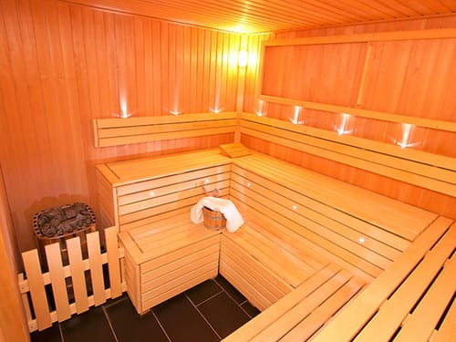 Moderne Sauna mit Holzbänken und Aufgusseimer