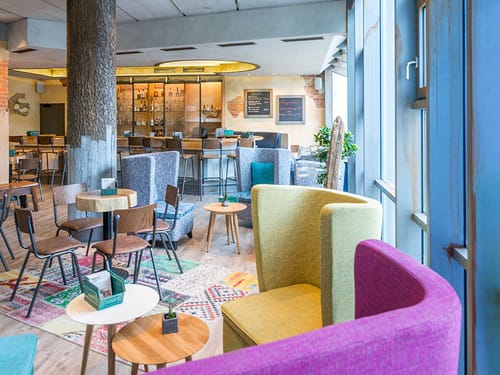 Bar mit bunten Sesseln, Tischen, Stühlen und Barhockern