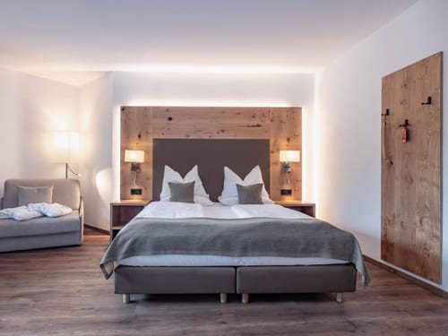 Modernes Hotelzimmer mit Doppelbett, Holzdetails und gemütlicher Beleuchtung.