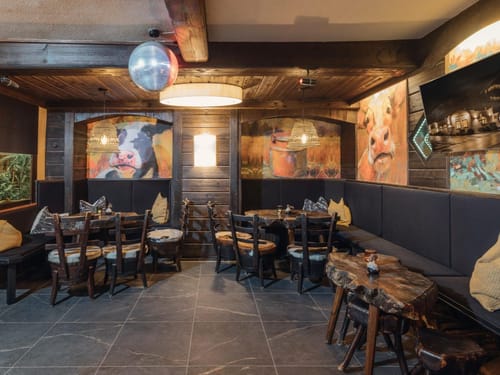 Gemütliches rustikales Restaurant mit Holzmöbeln und Wandkunst von Kühen.