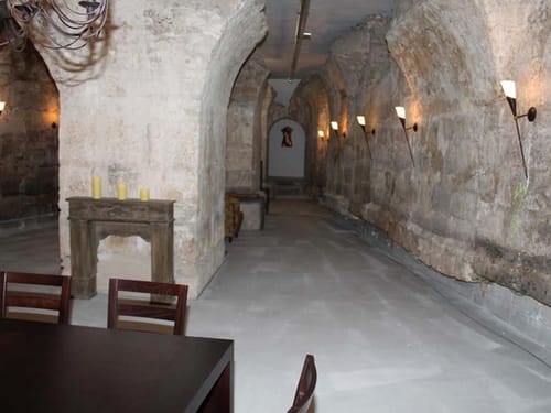 Gewölbe mit Tischen und Stühlen und Lampen an der Wand