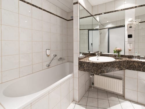 Badbereich mit Badewanne, Waschtisch und großem Wandspiegel