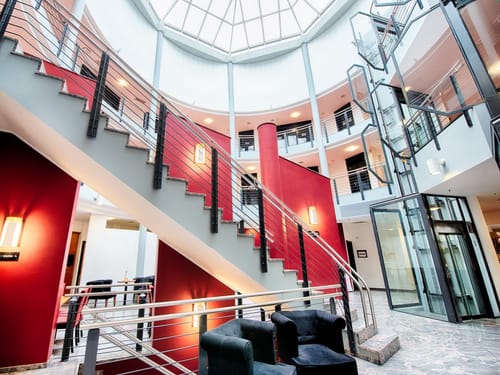 große Hotellobby mit Treppenaufgang und Fahrstuhl