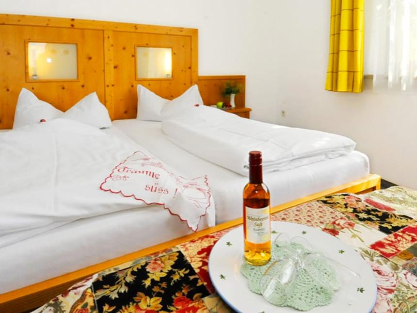 Doppelzimmer mit Doppelbett, kleinen Tisch mit einer Weinflasche und Gläsern