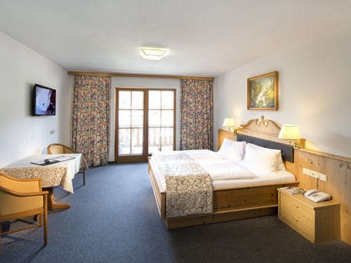 geräumiges Doppelzimmer mit Doppelbett, TV, Tisch und zwei Stühlen