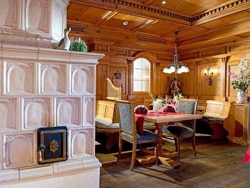 Hotel Restaurant mit verschiedenen Tischgruppen und Kachelofen