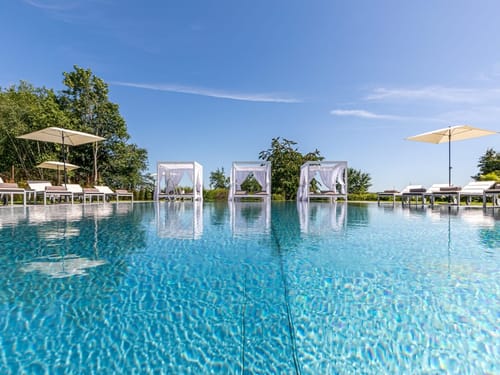 Poolanlage im Garten mit Relaxliegen und Sonnenschirme
