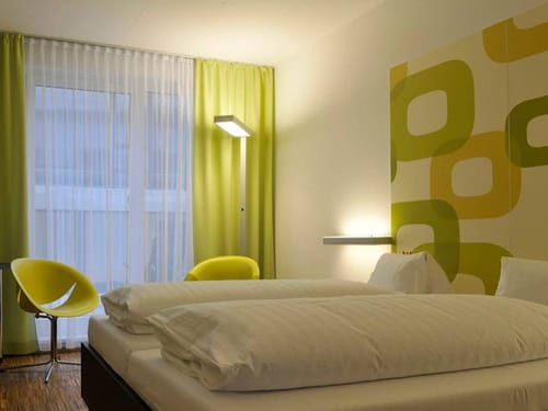 Standard Doppelzimmer mit Boxspringbett, grünen Vorhängen und Sesseln