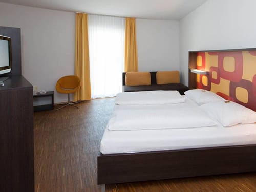 Doppelbett, kleine Couch, Sessel und TV im Doppelzimmer