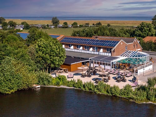 Hotelansicht mit Terrasse und anlilegendem See