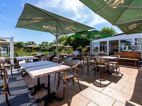 Hotelterrasse mit verschiedenen Tischgruppen direkt am See