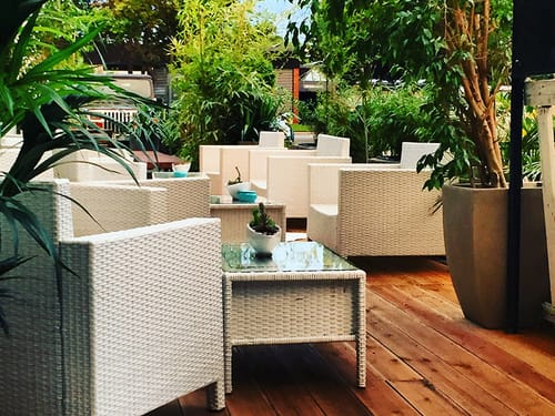 Hotelterrasse mit weißen Rattanmöbeln und Glastischen
