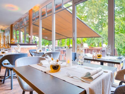 festlich gedeckte Tische im Wintergarten mit Panoramfenster