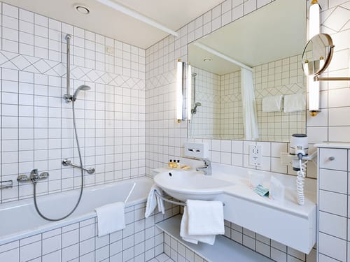 Badbereich mit Badewanne, Kosmetikspiegel, Föhn und Waschtisch