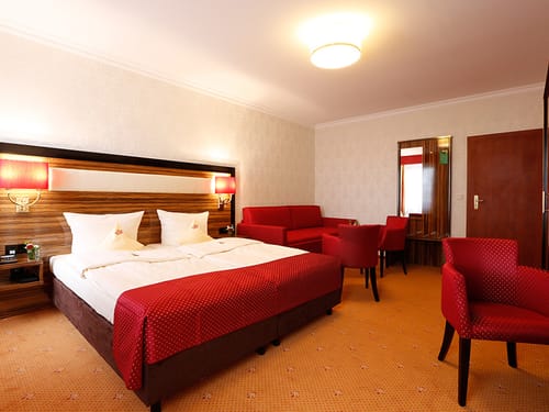 Doppelzimmer mit Doppelbett, Sofa, Stühlen und Sessel