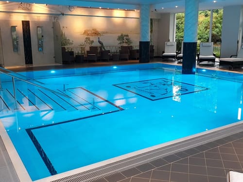 großer Indoor Pool mit Wellnessliegen am Rande