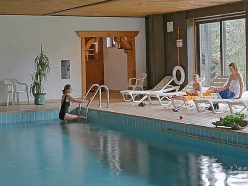 Indoor Pool mit Hotelgästen auf den Relaxliegen
