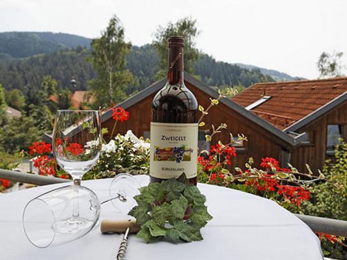 Zwei Weingläser und eine Flasche Rotwein auf dem Tisch der Hotelterrasse