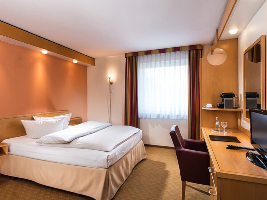 Gemütliches Hotelzimmer mit Doppelbett und Arbeitsbereich