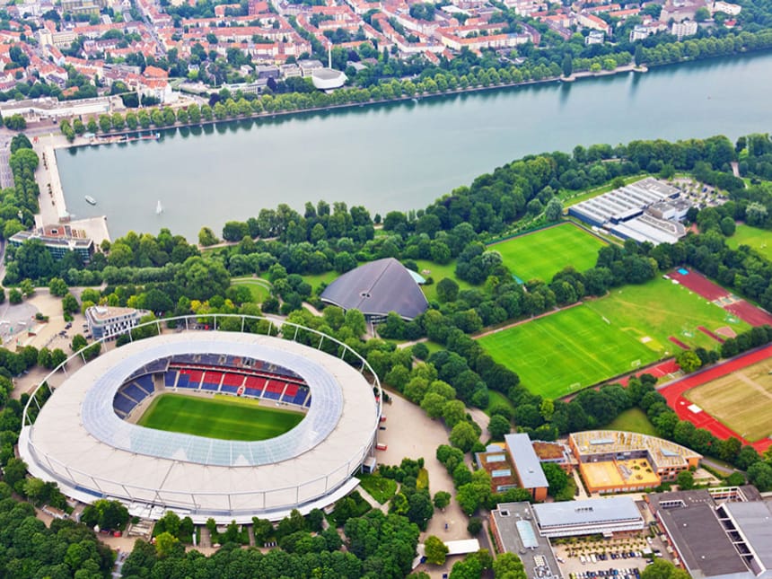 Luftaufnahme eines Stadions und umliegender Parklandschaft an einem See