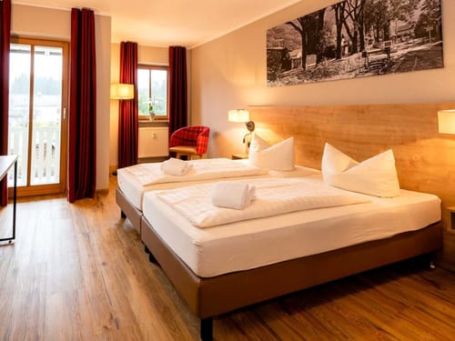 modernes Zweibettzimmer mit Doppelbett, Sessel, Schreibtisch und TV