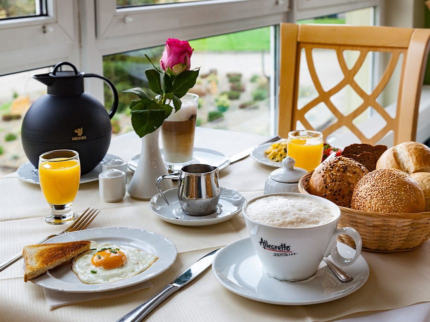 gedeckter Frühstückstisch mit einer Auswahl an Saft, Kaffee, Ei und verschiedenen Backwaren