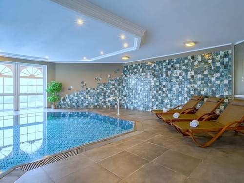Wellness Bereich mit Indoor Pool und Relaxliegen am Rande