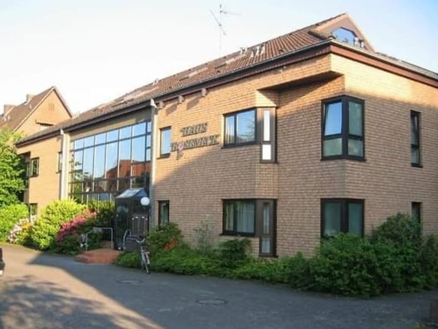 Modernes Hotel in sonniger Umgebung mit großen Fenstern und gepflegter Gartenanlage.